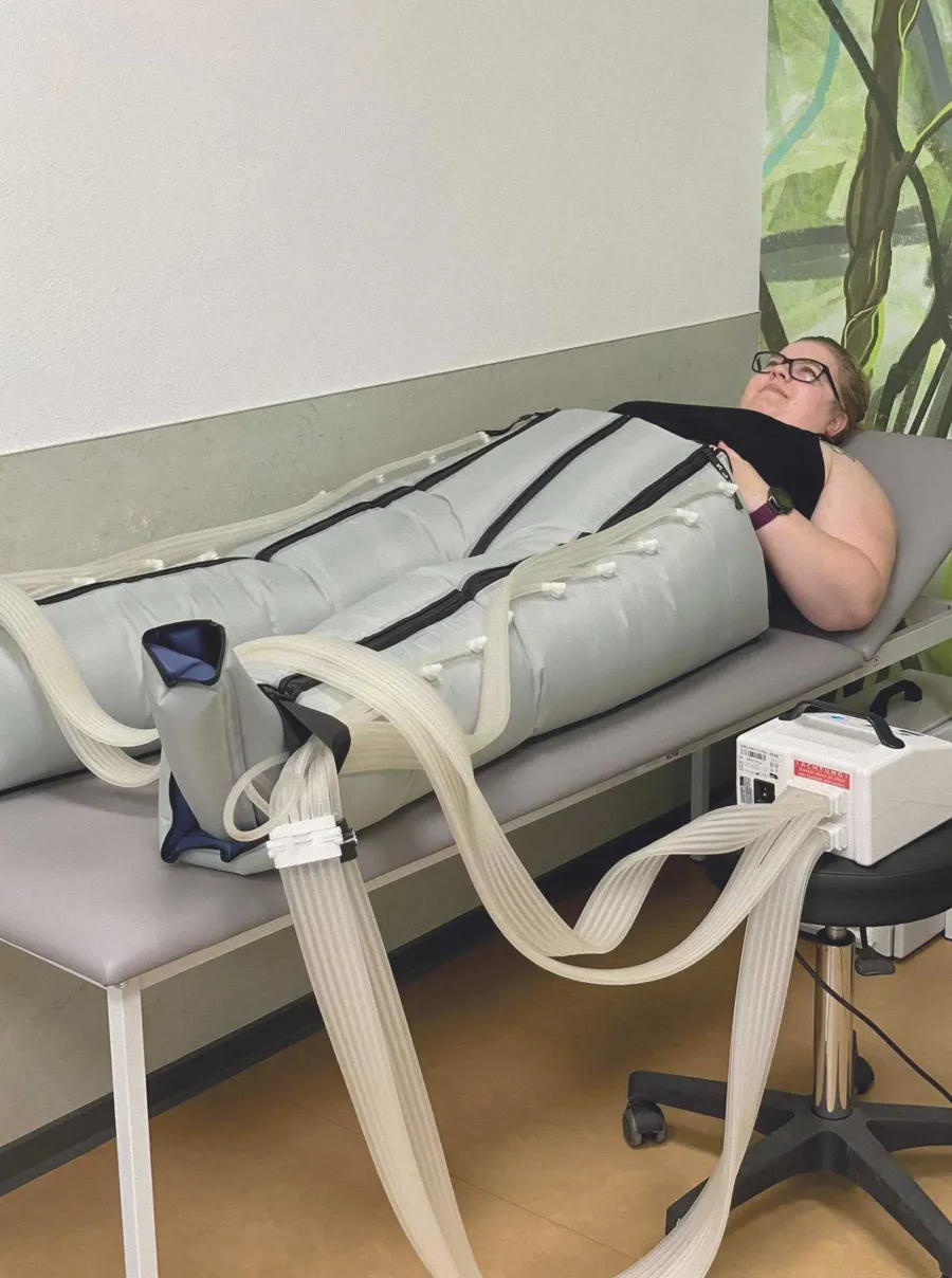 Patientin liegt mit Kompressionsmanschetten an Beinen bei AIK-Therapie.