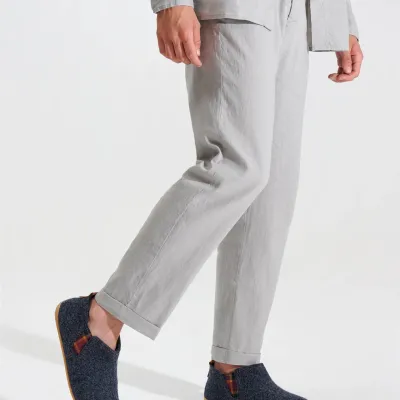 Graue Filz-Slipper mit Kork-Sohle, getragen zu heller Leinenhose.