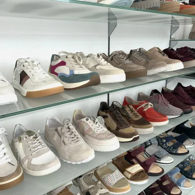Glasregale mit Sneakern, Sandalen und Komfortschuhen in verschiedenen Farben