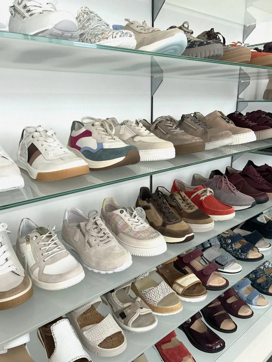 Glasregale mit Sneakern, Sandalen und Komfortschuhen in verschiedenen Farben