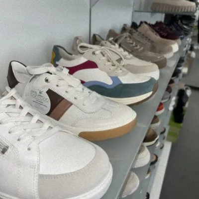 Bequemschuhe in Weiß, Beige und Blau auf Glasregalen im Schaufenster