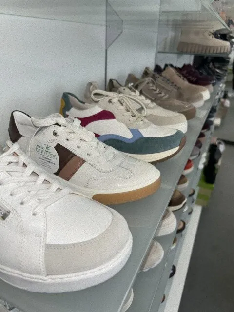 Bequemschuhe in Weiß, Beige und Blau auf Glasregalen im Schaufenster