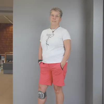 Frau mit elektronischer Fußheber-Orthese am Knie in Shorts und T-Shirt