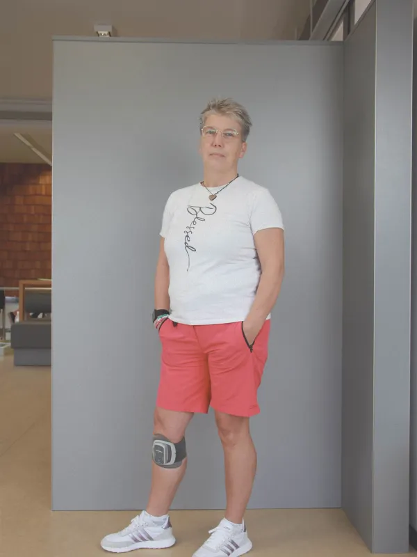 Frau mit elektronischer Fußheber-Orthese am Knie in Shorts und T-Shirt