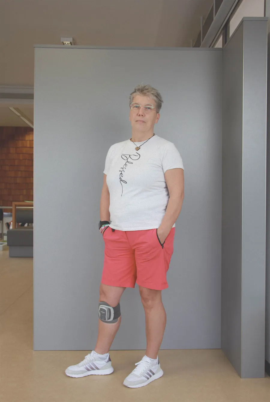 Frau mit elektronischer Fußheber-Orthese am Knie in Shorts und T-Shirt