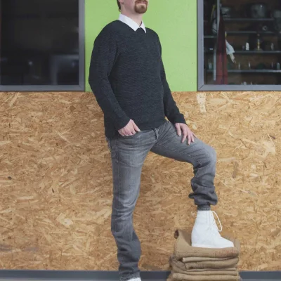 Mann stellt einen Fuß mit orthopädischem Schuh auf Stoffstapel