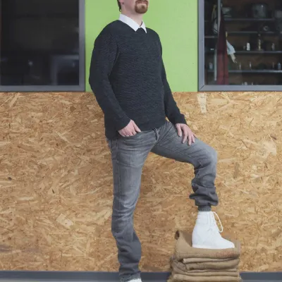 Mann stellt einen Fuß mit orthopädischem Schuh auf Stoffstapel