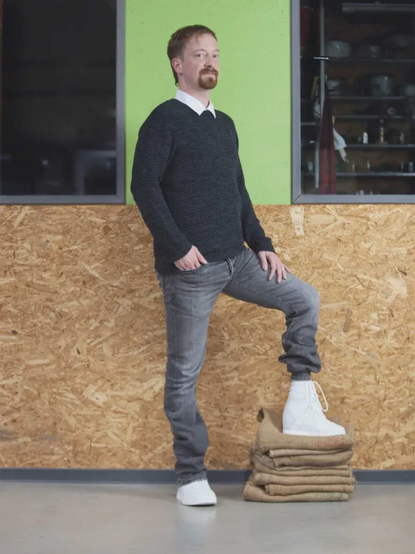 Mann stellt einen Fuß mit orthopädischem Schuh auf Stoffstapel