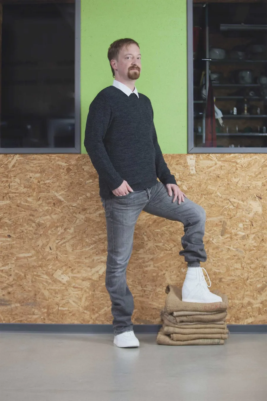 Mann stellt einen Fuß mit orthopädischem Schuh auf Stoffstapel