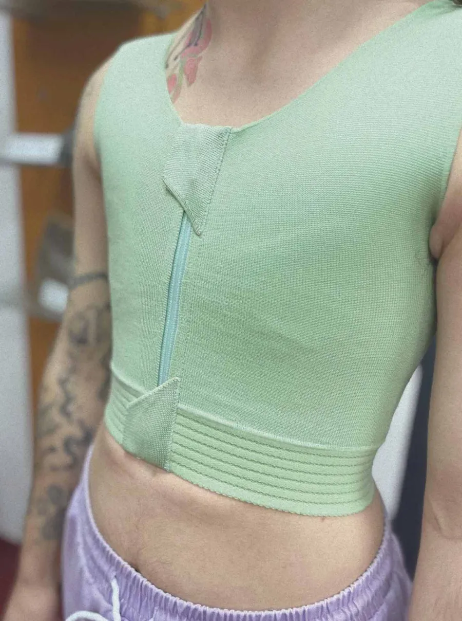 Grüne Kompressionsbandage mit Reißverschluss vorne am Oberkörper.