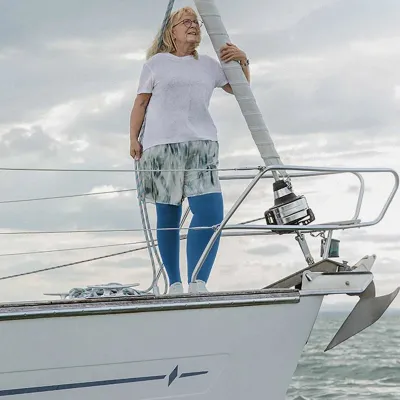 Frau mit blauen Kompressionsstrümpfen steht auf Segelboot am Bug