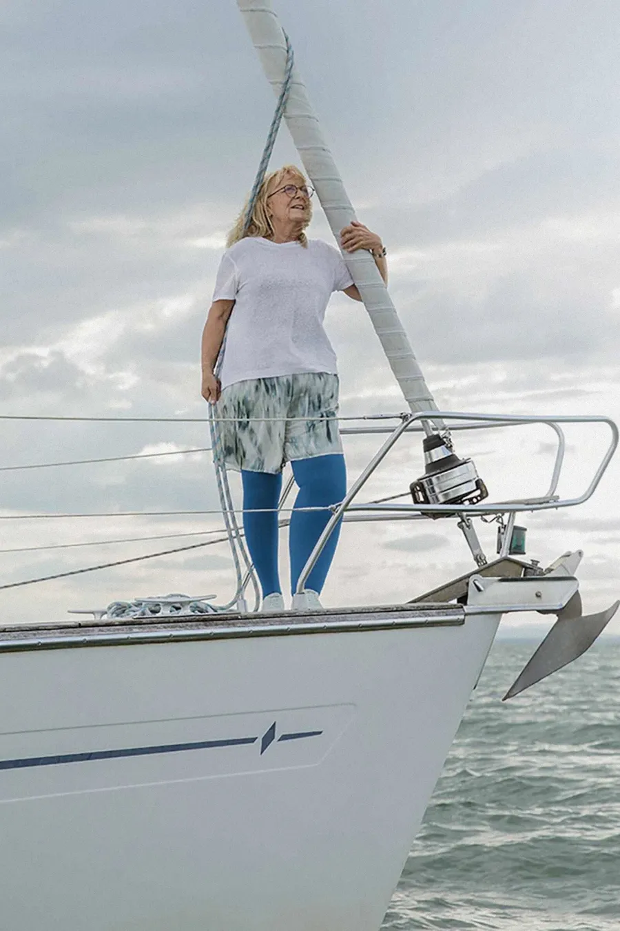 Frau mit blauen Kompressionsstrümpfen steht auf Segelboot am Bug