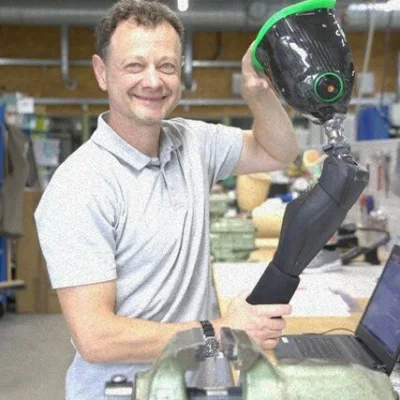 Mitarbeiter hält Beinprothese mit Kniegelenk in der Werkstatt