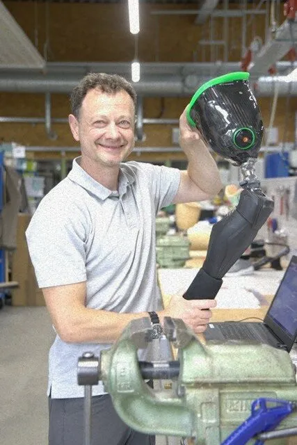 Mitarbeiter hält Beinprothese mit Kniegelenk in der Werkstatt
