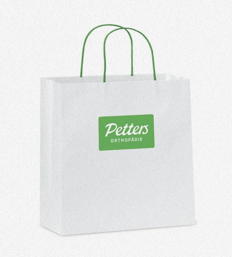Weiße Papiertragetasche mit grünen Kordelgriffen und Petters Orthopädie Logo
