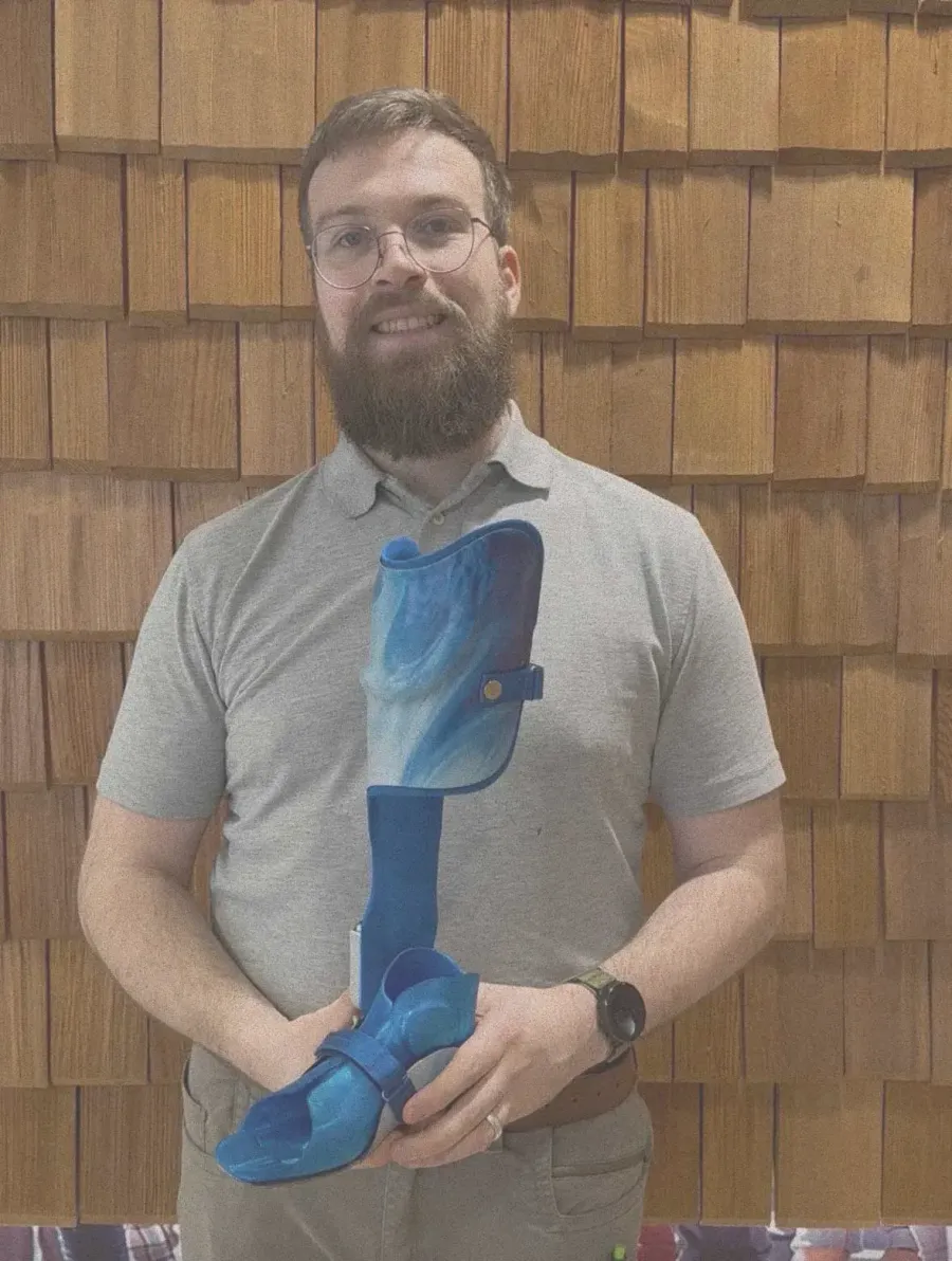 Mann hält blaue Unterschenkelorthese mit Fußteil in beiden Händen.