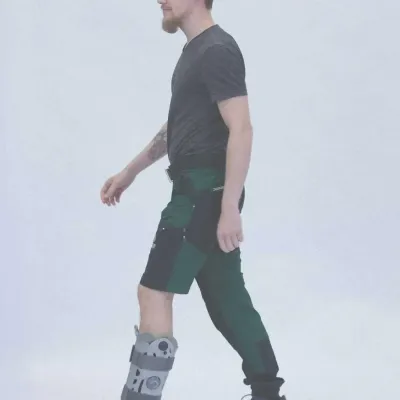 Mann geht mit stabilisierender Unterschenkelorthese am linken Fuß.