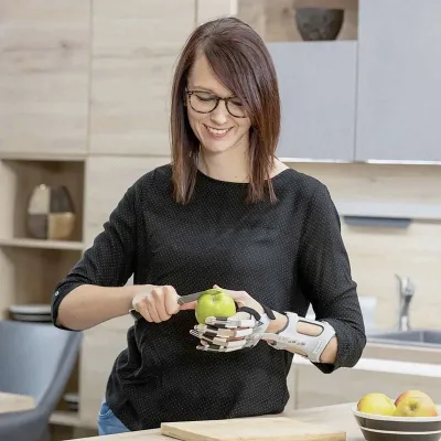 Frau mit Handorthese hält Apfel und schneidet ihn mit einem Messer.